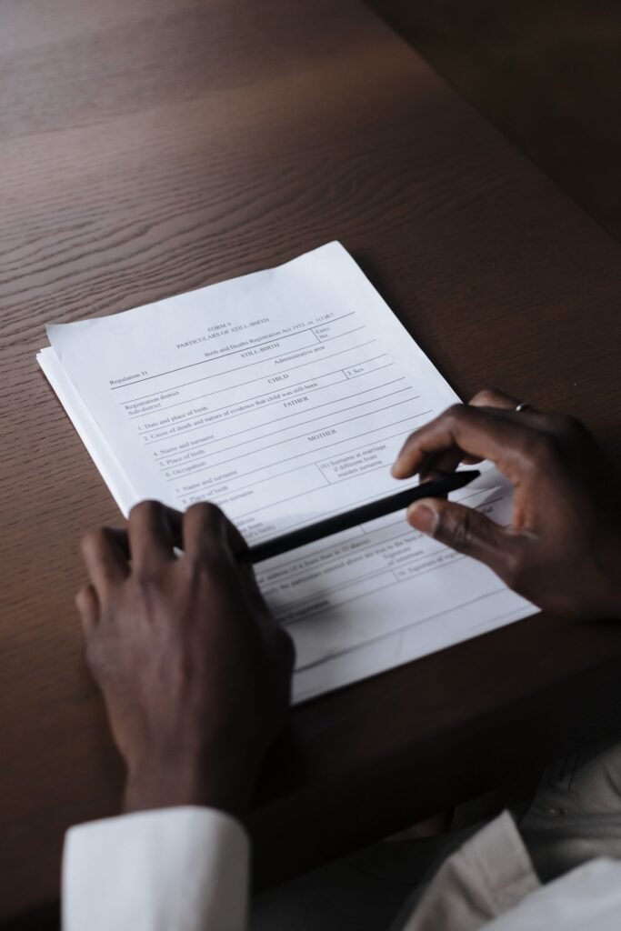 Hands holding a pen while reviewing documents on a wooden table