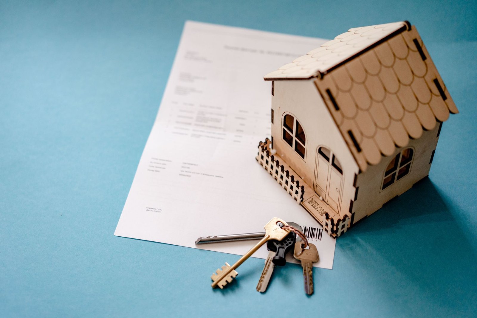Wooden house model, keys and paperwork illustrating home ownership